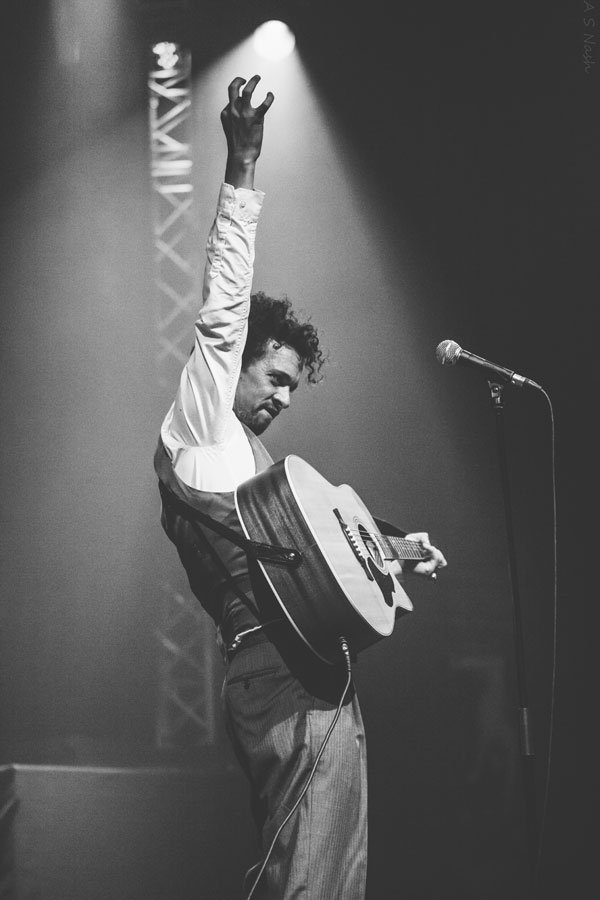Comedian Elliot Mason raising his hand on stage at the Komedia in Bath for The Ministry of Burlesque. Photograph by Andrew Nash.